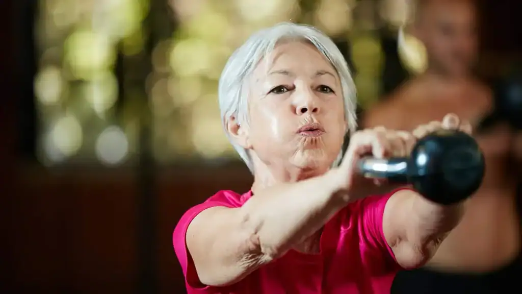 Older woman doing weight training West Mersea to help her strength and longevity 