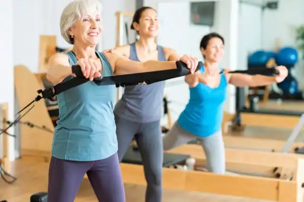 Toning Arms After 60: Empowering Womens Fitness Through Effective Weight Training 2 older woman doing weight training West Mersea and resistance in the gym to tone upper arms